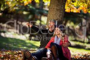 Happy couple sitting under tree at park