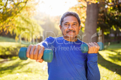 Mature man exercising with dumbbell at park