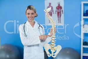 Portrait of physiotherapist holding spine model