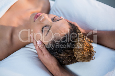 Woman receiving head massage from physiotherapist