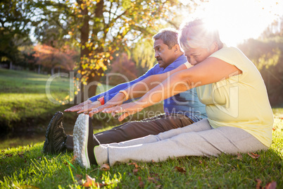 Mature couple stretching on field at park