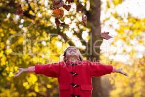 Happy girl throwing autumn leaves