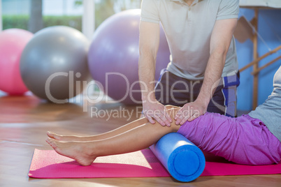 Physiotherapist assisting woman while exercising on exercise mat