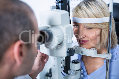 Optometrist examining female patient on slit lamp