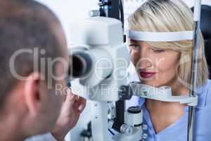 Optometrist examining female patient on slit lamp