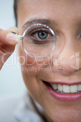 Female optometrist looking through magnifying glass