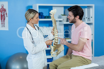 Physiotherapist explaining the spine model to patient Physiotherapist explaining the spine model to patient