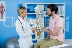 Physiotherapist explaining the spine model to patient