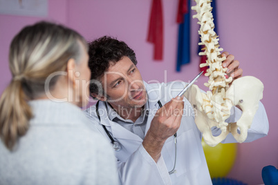 Physiotherapist explaining the spine model to patient