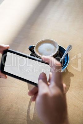 Female hands photographing a coffee cup