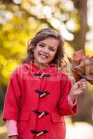 Portrait of girl holding autumn leaves at park