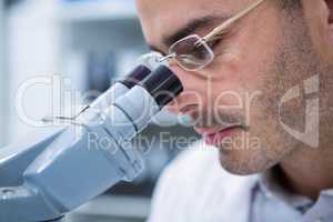 Male optometrist looking through microscope