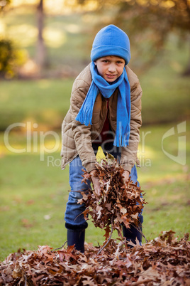 Portrait of boy holding dry leaves at park during autumn