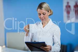 Physiotherapist looking at medical report while having coffee