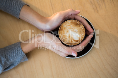 Woman holding cup of coffee on table