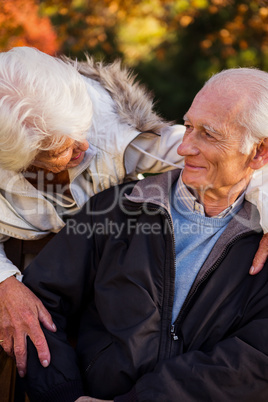 A senior woman tenderly looking at her husband sitting