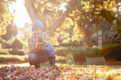 Boy holding autumn leaves at park
