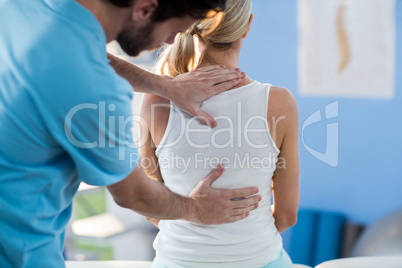 Male physiotherapist giving back massage to female patient