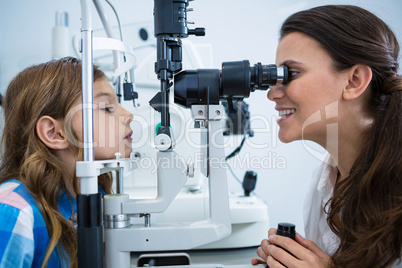 Female optometrist examining young patient on slit lamp