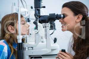 Female optometrist examining young patient on slit lamp