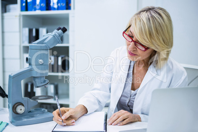 Optometrist writing in file at ophthalmology clinic