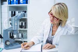 Optometrist writing in file at ophthalmology clinic