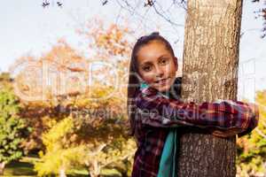 Portrait of smiling girl hugging tree