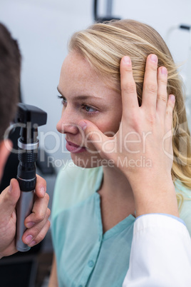 Optometrist examining female patient through ophthalmoscope