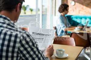 Man reading a business newspaper in coffee shop