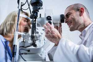 Optometrist examining female patient on slit lamp