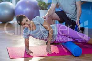 Physiotherapist assisting woman while exercising on exercise mat