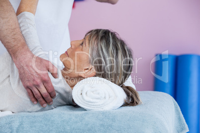 Physiotherapist massaging a senior womans shoulder