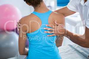 Physiotherapist giving back massage to female patient