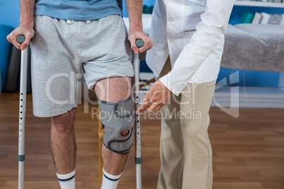 Physiotherapist helping patient to walk with crutches