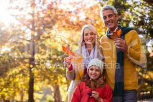 Portrait of happy family holding leaves against trees
