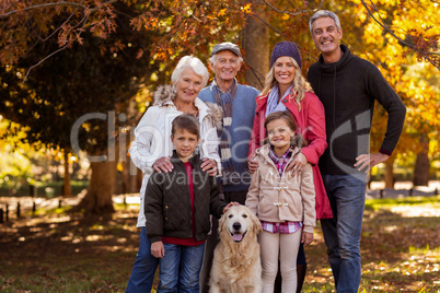 Multi-generation family standing with dog at park