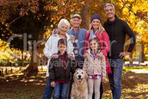 Multi-generation family standing with dog at park