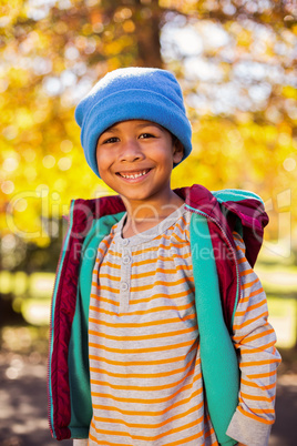 Happy boy standing against autumn tree