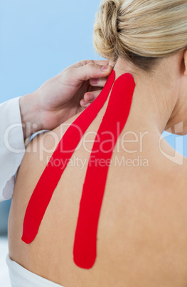 Physiotherapist sticking tape on female patient