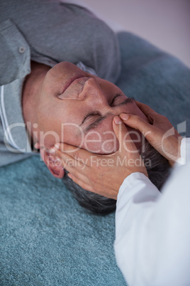 Senior man receiving head massage from physiotherapist