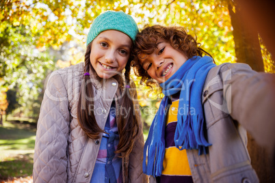 Cheerful siblings taking selfie in park