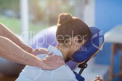 Physiotherapist giving shoulder massage to a female patient