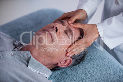 Senior man receiving head massage from physiotherapist