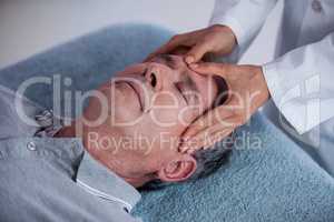 Senior man receiving head massage from physiotherapist
