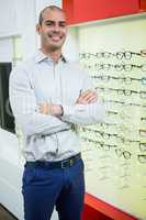 Smiling male optician standing with arms crossed