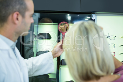 Female customer wearing spectacles and checking in mirror