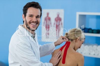 Physiotherapist sticking tape on female patient