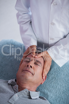 Senior man receiving head massage from physiotherapist