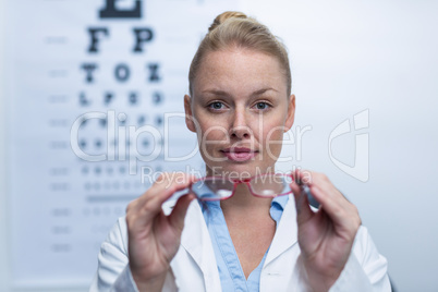 Beautiful female optometrist holding spectacles