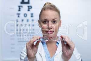 Beautiful female optometrist holding spectacles